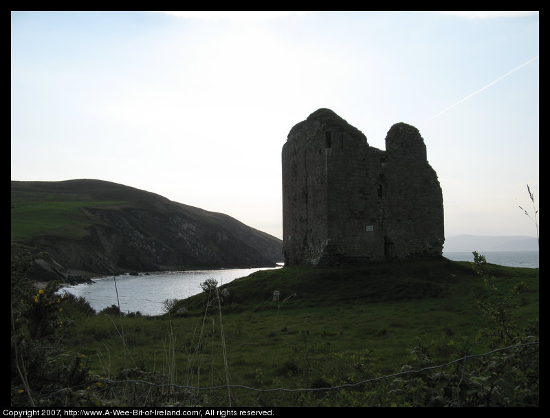 A ruined castle next to the ocean with a late bronze age or early iron age ring fort on the opposite hill.