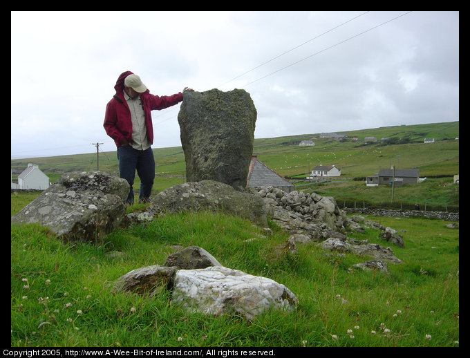 A standing stone marking ancient burials with a man standing next to it.