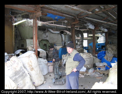 Two men with a hand truck moving bags of wool