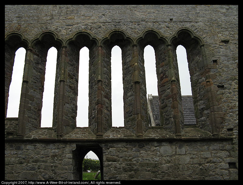 A ruined cathedral built of stone. There is no roof. The view is from the interior through window openings to the side. There is no glass in the window openings.