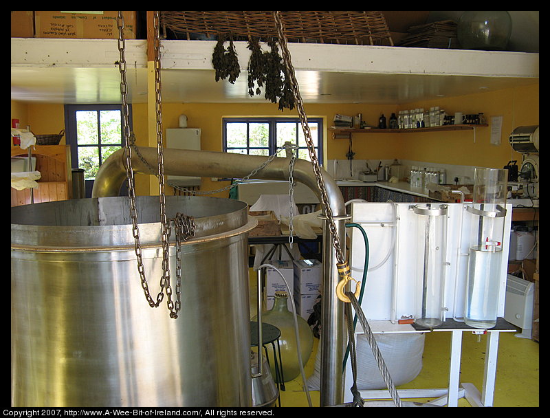 Equipment for making perfume and shelves full of bottles and jugs and dried herbs hanging from the loft.