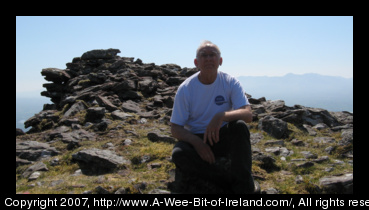 John Moyer sitting on the wall of the promontory fort at the top of Caherconree Mountain, County Kerry, Ireland.