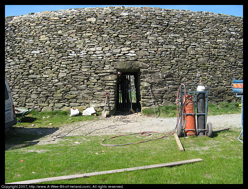 A tall curved stone wall with an opening covered by a lintel stone.