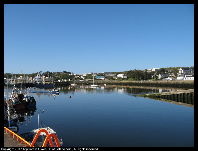 A bright sunny day with reflections on the still harbor water and many boats and ships