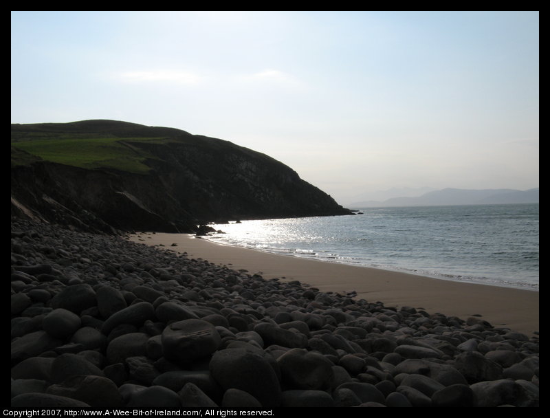 Looking from Minard Castle at a storm beach of sand next to the ocean and smooth rounded boulders above the sand that are said to have been thrown there by storms.