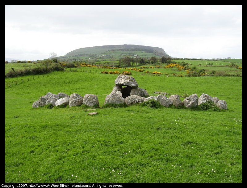 Two structures of very large stones that were once part of a burial complex built 5000 or 6000 years ago. In the background is a mountain with a cairn at the top.