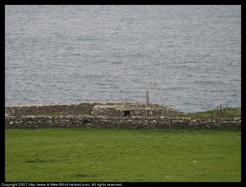 Stone Fort surrounded by stone walls and green grass at the edge of a cliff next to the ocean.