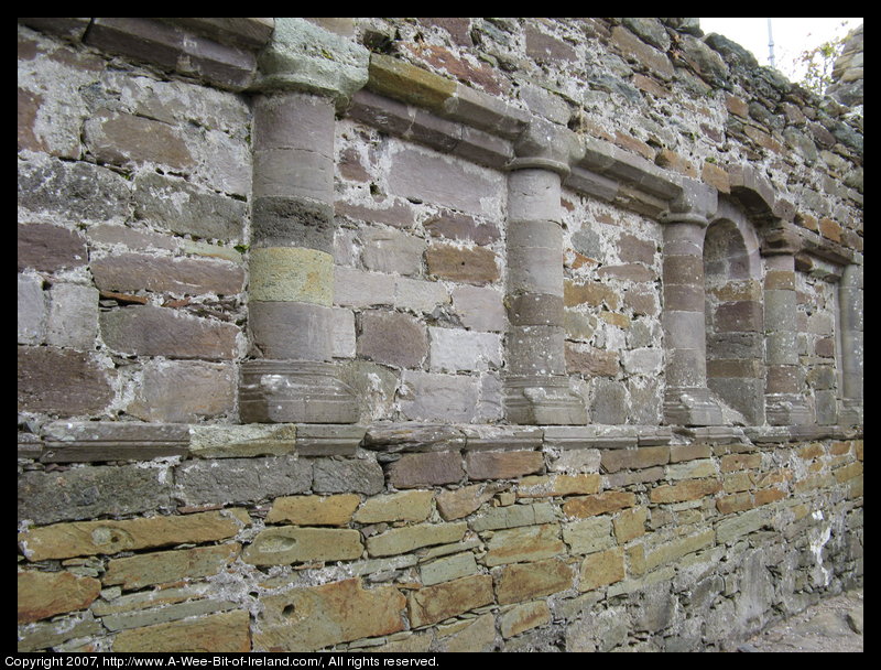 The stone wall of the ruined church is carved to look like pillars.