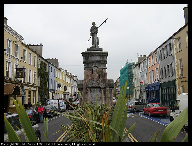 A statue of a pikeman in the middle of a busy street.