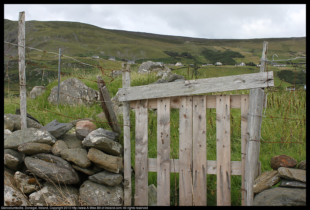 A wooden gate with a megalithic tomb beyond the gate.