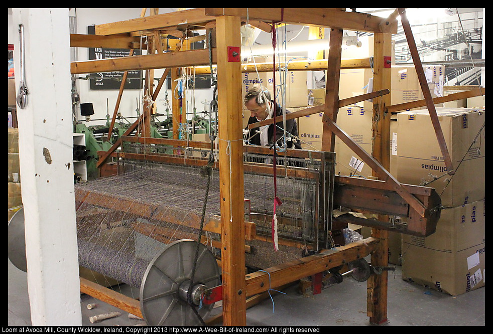 A man is working a loom weaving cloth.