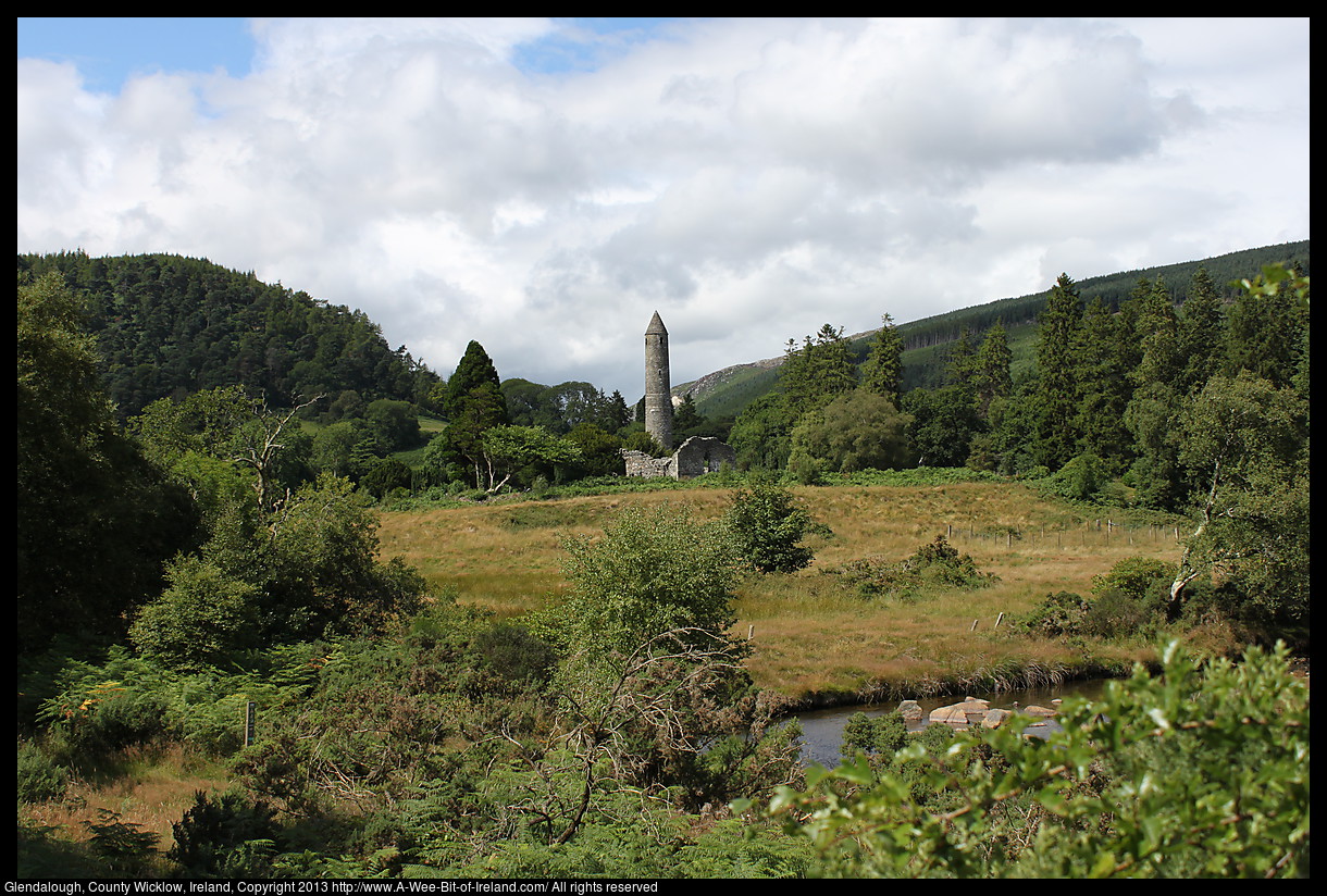 A round tower in a mountain valley near a stream.