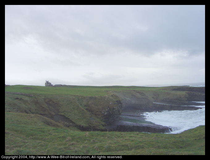 Classiebawn Castle on Mullaghmore Head next to the ocean with green grass and waves crashing onto rocks.