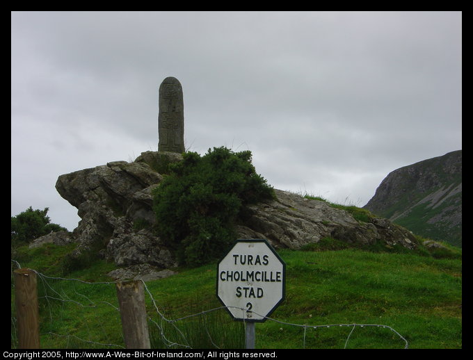 Slab of stone with a crosses incised. It is on a rocky outcrop.