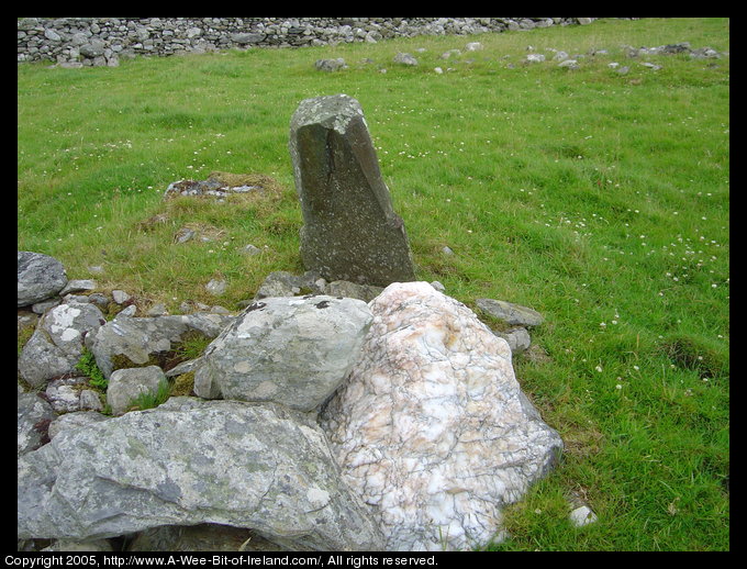 A standing stone marking ancient burials with a large white quartz rock
  next to it.