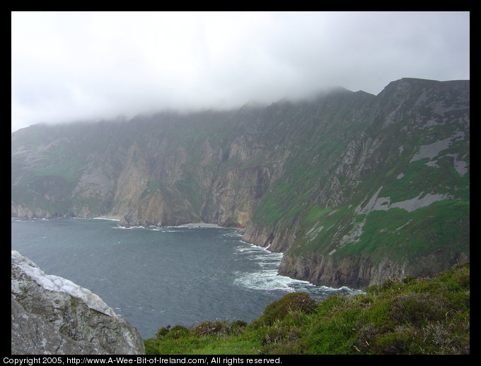 Slieve League sea cliffs. There is rain obscuring the top of the cliffs.