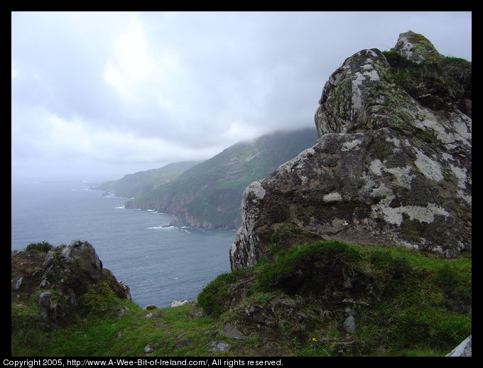 Slieve League sea cliffs with rain on top and large rock in foreground.