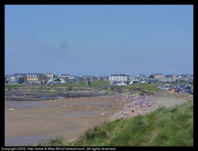 People crowed onto a sandy beach near rocks that wrecked part of the
 Spanish Armada